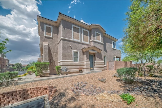 view of front facade with fence and stucco siding
