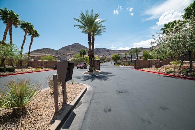 view of street with curbs, a gated entry, and a mountain view