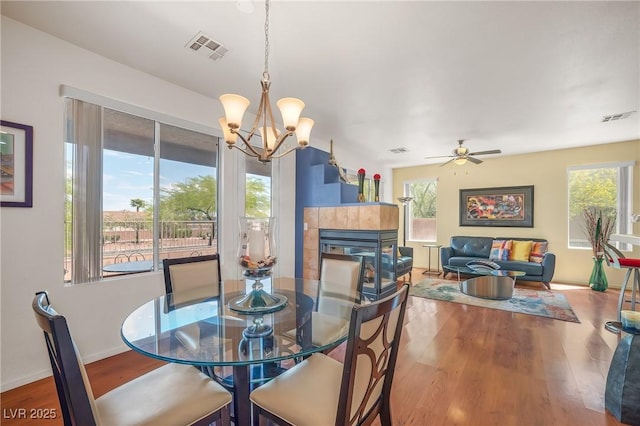 dining room with visible vents, wood finished floors, and ceiling fan with notable chandelier