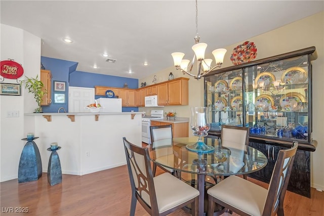 dining room featuring an inviting chandelier, baseboards, recessed lighting, and wood finished floors