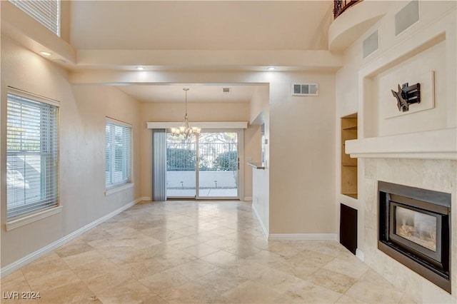 unfurnished living room with built in features, a high end fireplace, and a chandelier