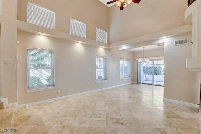 unfurnished room with a high ceiling and ceiling fan with notable chandelier