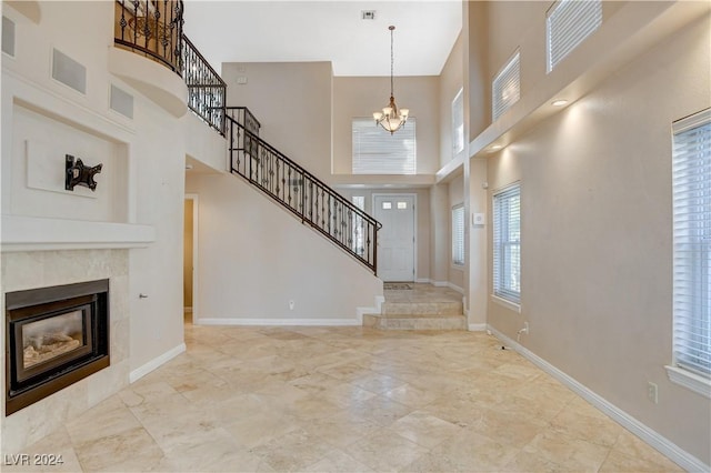 foyer entrance with a notable chandelier, a towering ceiling, and a high end fireplace