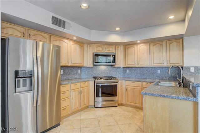 kitchen with light stone countertops, sink, stainless steel appliances, decorative backsplash, and light brown cabinetry