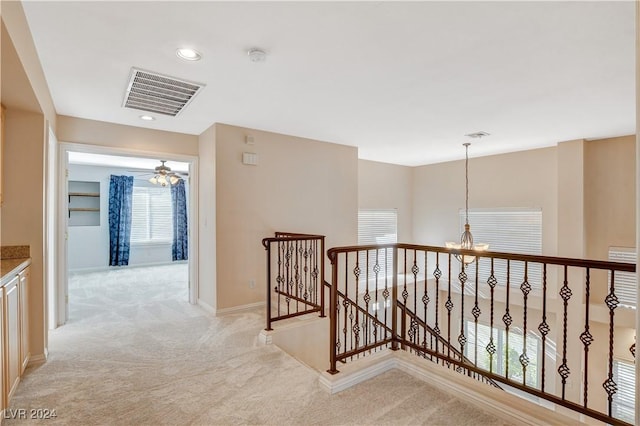 hallway featuring light carpet and a chandelier