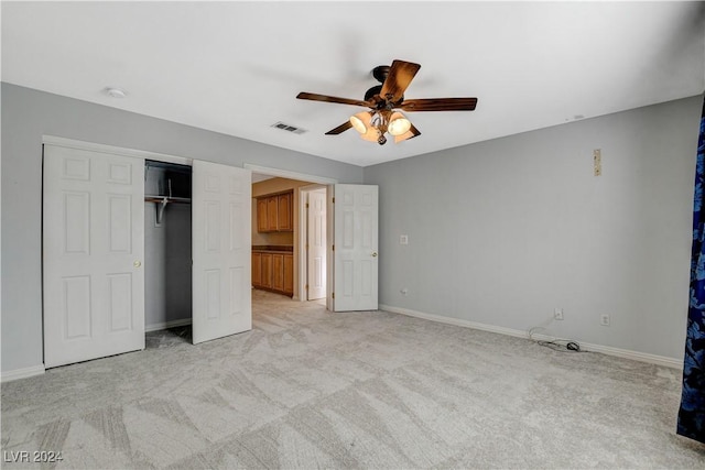 unfurnished bedroom featuring light carpet, a closet, and ceiling fan