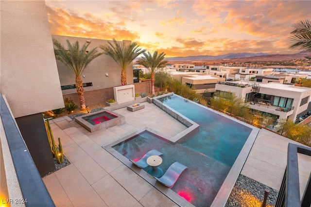 pool at dusk with an in ground hot tub and a mountain view