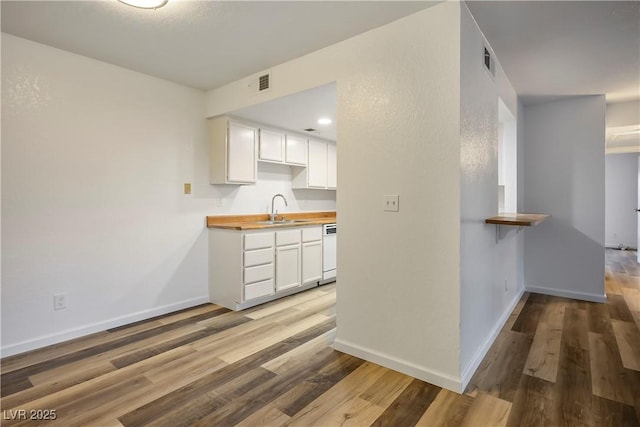 kitchen with white cabinetry, sink, wood counters, white dishwasher, and light hardwood / wood-style floors