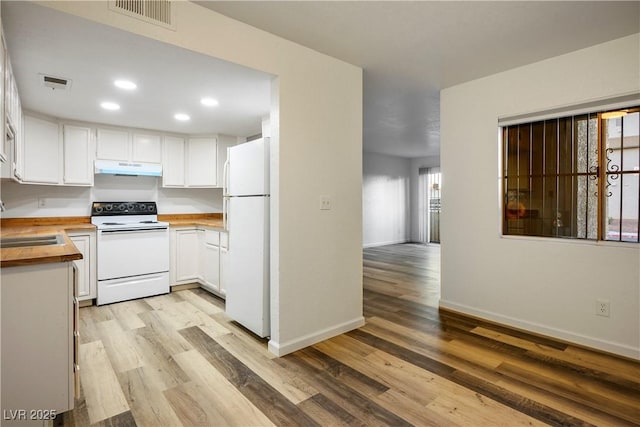 kitchen featuring butcher block countertops, white cabinetry, light wood-type flooring, and white appliances