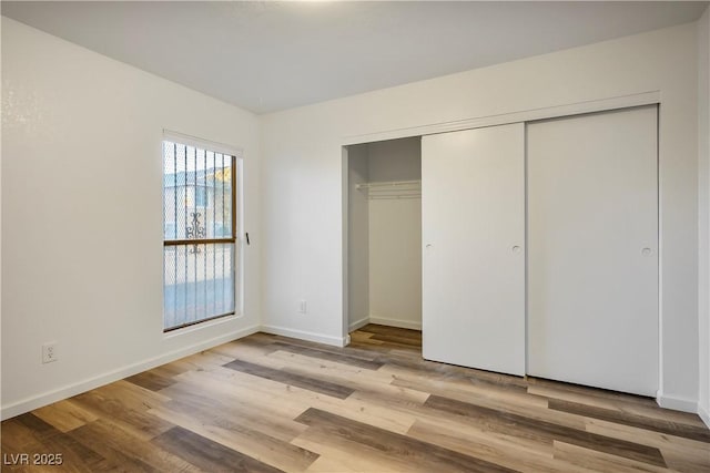 unfurnished bedroom with light hardwood / wood-style flooring and a closet