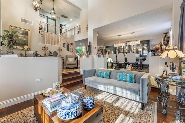 living room featuring a towering ceiling, dark hardwood / wood-style floors, and a chandelier