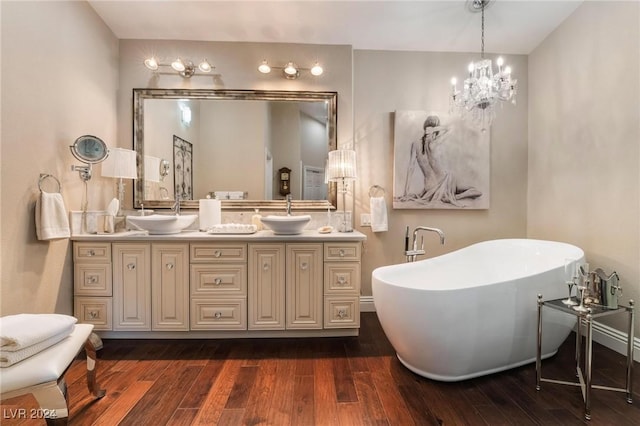 bathroom with wood-type flooring, vanity, an inviting chandelier, and a tub to relax in