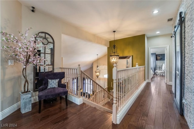 corridor featuring dark hardwood / wood-style floors, a barn door, a chandelier, and vaulted ceiling