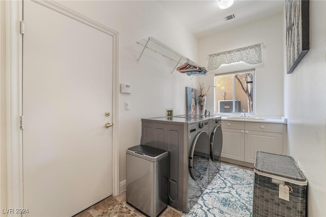 washroom with cabinets, washer and clothes dryer, and sink