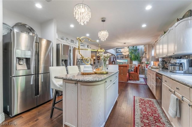 kitchen with decorative light fixtures, dark hardwood / wood-style flooring, a center island, a notable chandelier, and stainless steel appliances