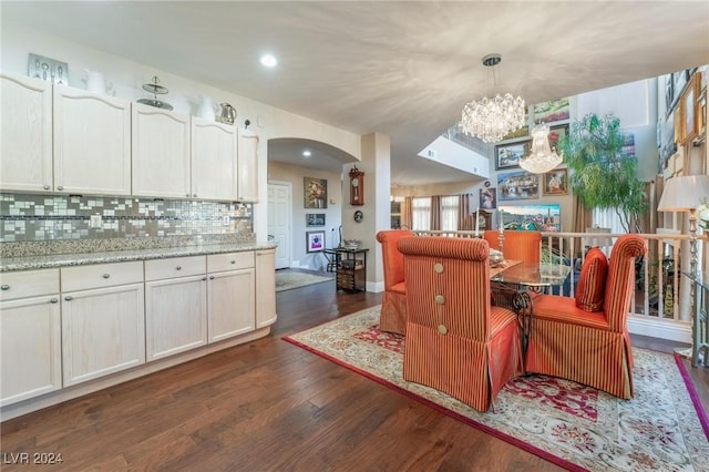 kitchen featuring decorative light fixtures, white cabinetry, dark hardwood / wood-style flooring, decorative backsplash, and light stone counters