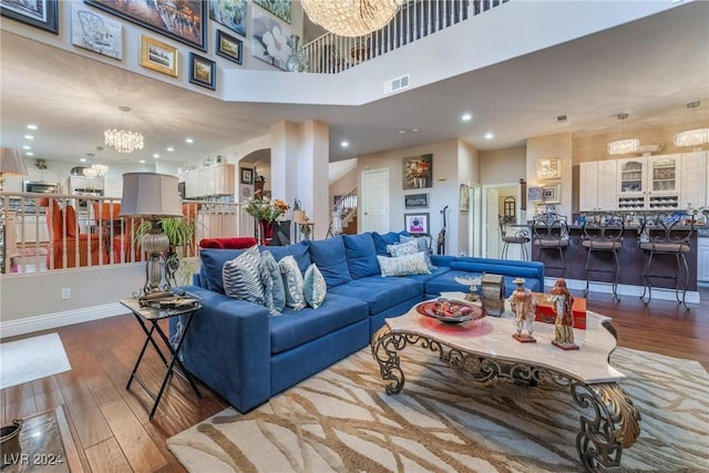 living room featuring dark hardwood / wood-style flooring, a notable chandelier, and a high ceiling