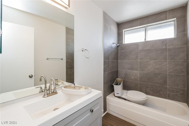 full bathroom with hardwood / wood-style floors, vanity, toilet, and tiled shower / bath