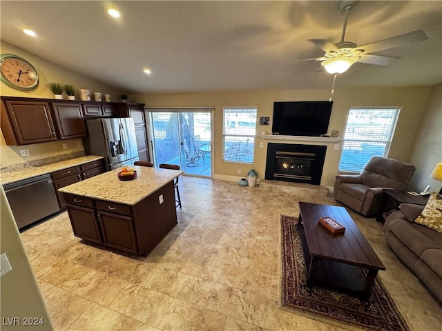 kitchen featuring appliances with stainless steel finishes, a center island, vaulted ceiling, and dark brown cabinets