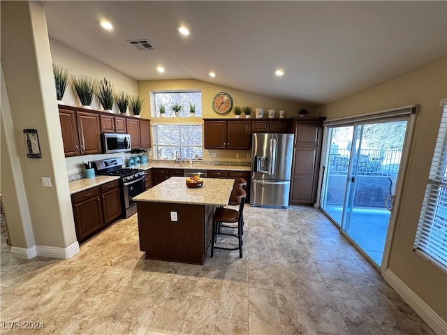 kitchen with a kitchen breakfast bar, a kitchen island, stainless steel appliances, and a wealth of natural light