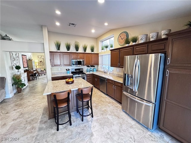 kitchen with a center island, lofted ceiling, sink, a kitchen bar, and stainless steel appliances