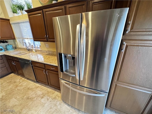 kitchen featuring light stone counters, sink, and stainless steel appliances