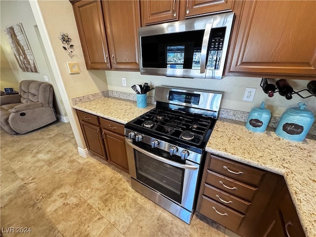 kitchen with light stone countertops and appliances with stainless steel finishes