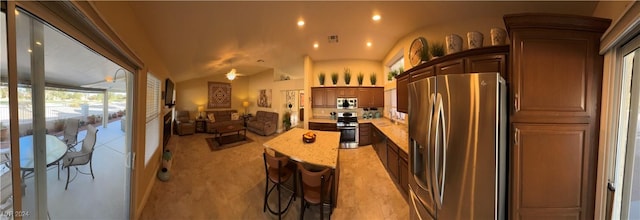 kitchen featuring a kitchen breakfast bar, stainless steel appliances, and lofted ceiling