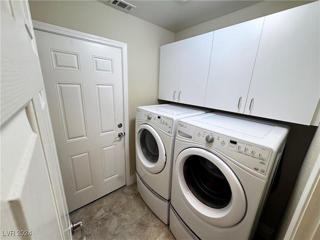 laundry area with cabinets, light tile patterned flooring, and washer and dryer