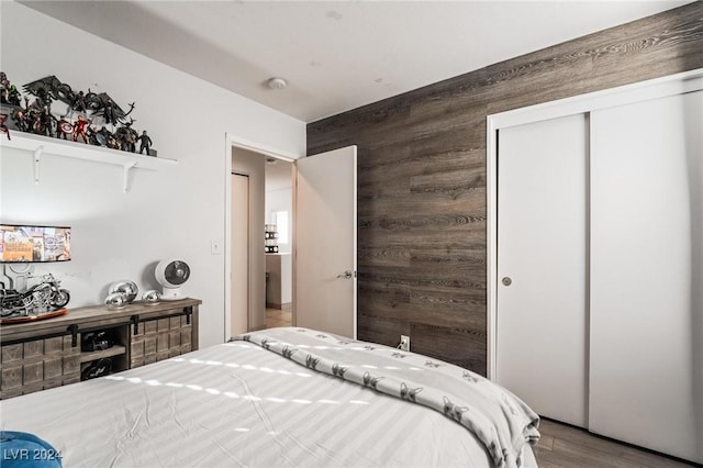 bedroom featuring hardwood / wood-style floors, a closet, and wooden walls