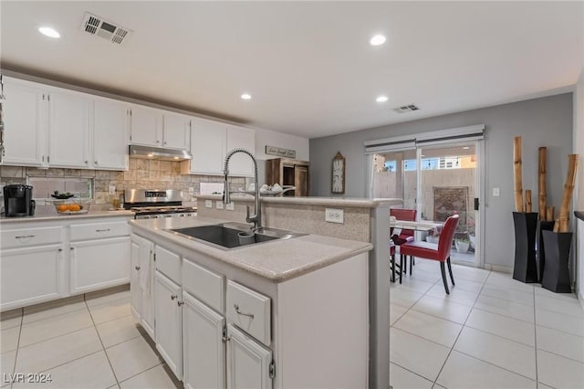 kitchen with sink, stainless steel range oven, white cabinetry, and an island with sink