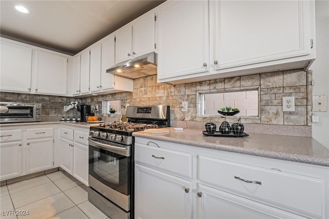 kitchen featuring white cabinets, decorative backsplash, stainless steel range with gas cooktop, and light tile patterned floors