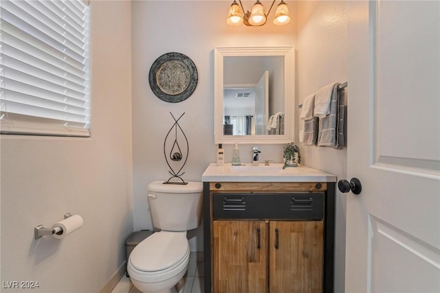 bathroom featuring tile patterned flooring, vanity, a chandelier, and toilet