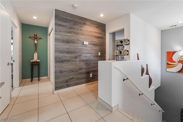 hallway with wood walls and light tile patterned flooring