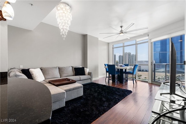 living room featuring expansive windows, dark wood-type flooring, and ceiling fan with notable chandelier