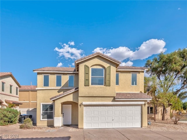 view of front of property with stucco siding, an attached garage, driveway, and a tiled roof