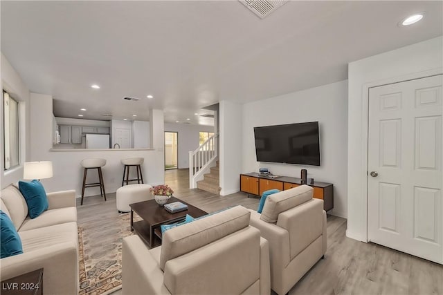 living room with recessed lighting, visible vents, light wood-style flooring, and stairs