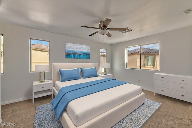 carpeted bedroom with visible vents, multiple windows, baseboards, and a ceiling fan