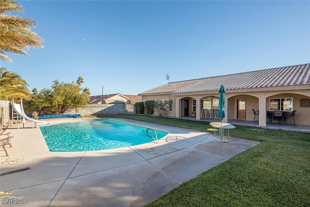 view of swimming pool featuring a yard, a patio, and a water slide