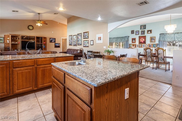 kitchen featuring lofted ceiling, a kitchen island with sink, ceiling fan with notable chandelier, decorative light fixtures, and light tile patterned flooring