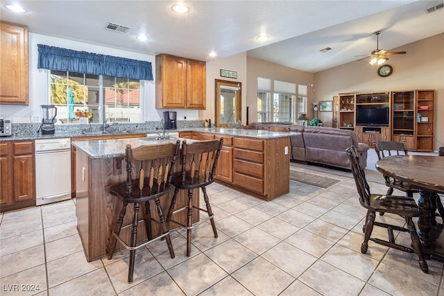 kitchen with light stone countertops, a kitchen island, plenty of natural light, and a breakfast bar area