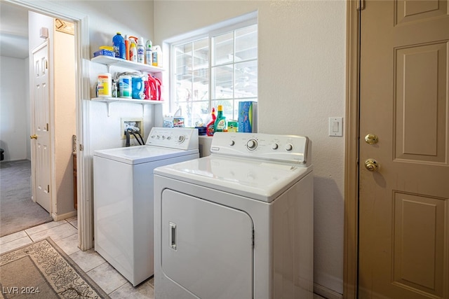 clothes washing area with light tile patterned floors and washer and dryer