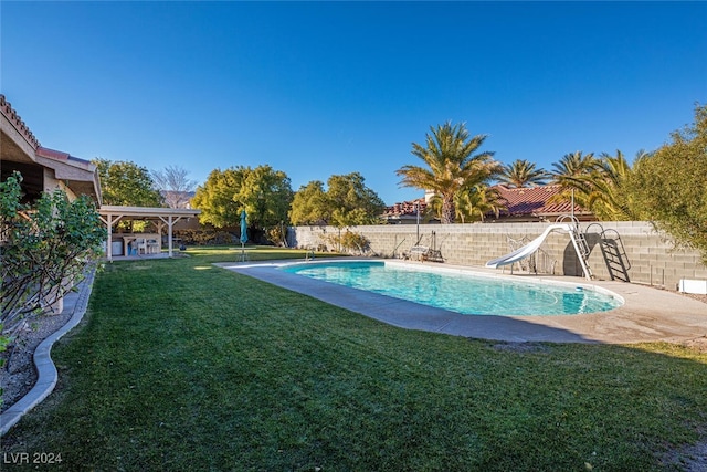 view of swimming pool with a lawn and a water slide