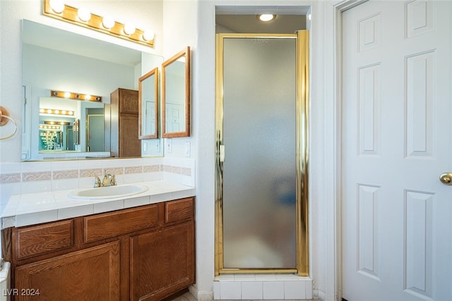 bathroom featuring vanity, a shower with door, and tasteful backsplash