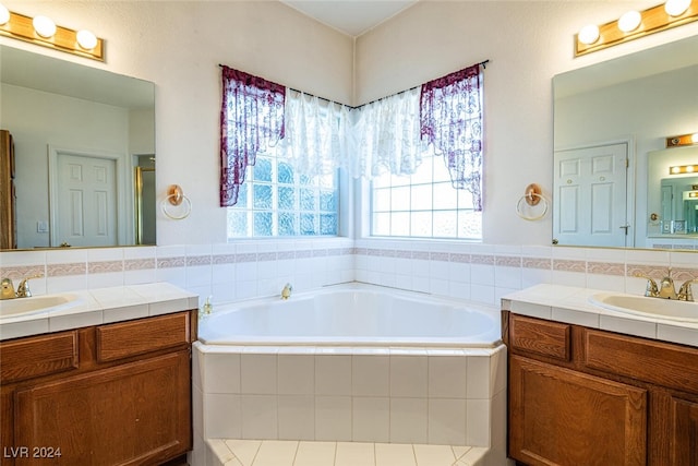 bathroom with vanity, a relaxing tiled tub, and plenty of natural light