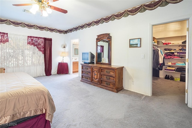 bedroom with light carpet, ensuite bathroom, a spacious closet, and ceiling fan