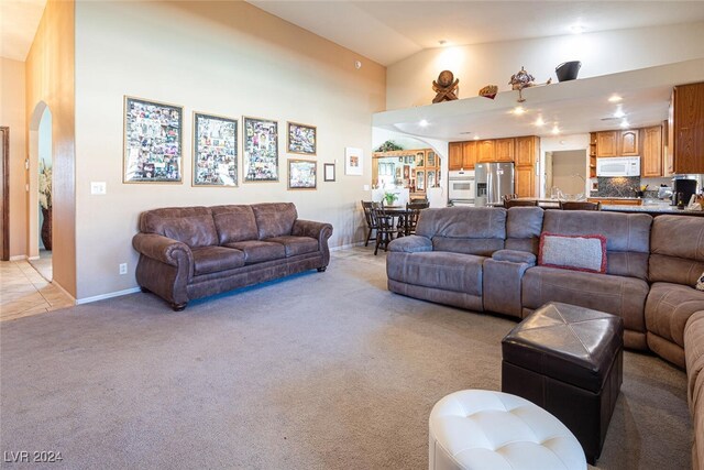 carpeted living room with high vaulted ceiling