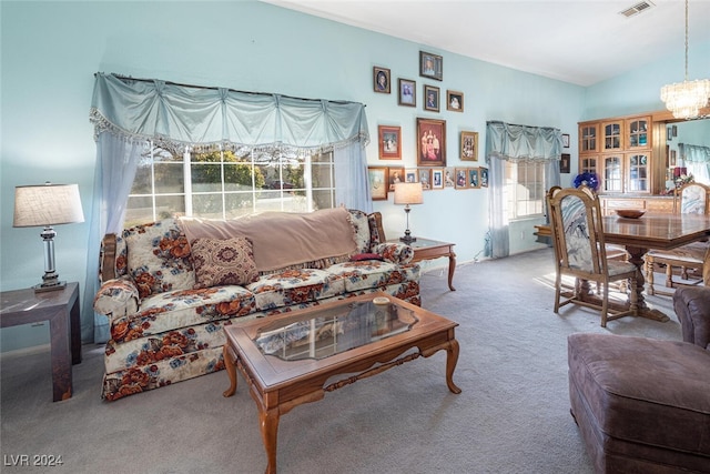 carpeted living room featuring a chandelier and vaulted ceiling