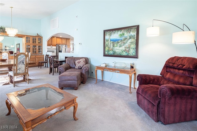 living room featuring light colored carpet, a high ceiling, and an inviting chandelier