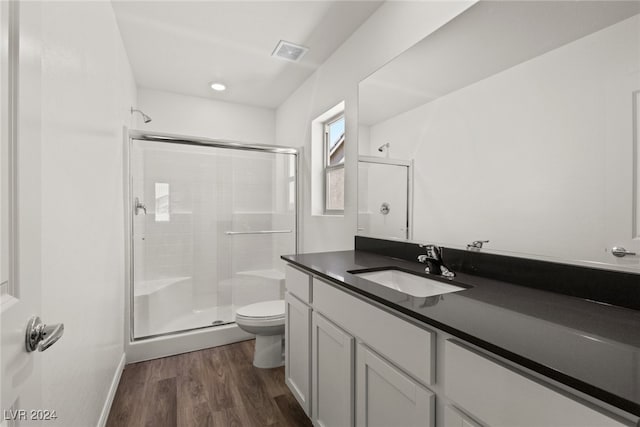 bathroom with hardwood / wood-style floors, toilet, an enclosed shower, and vanity